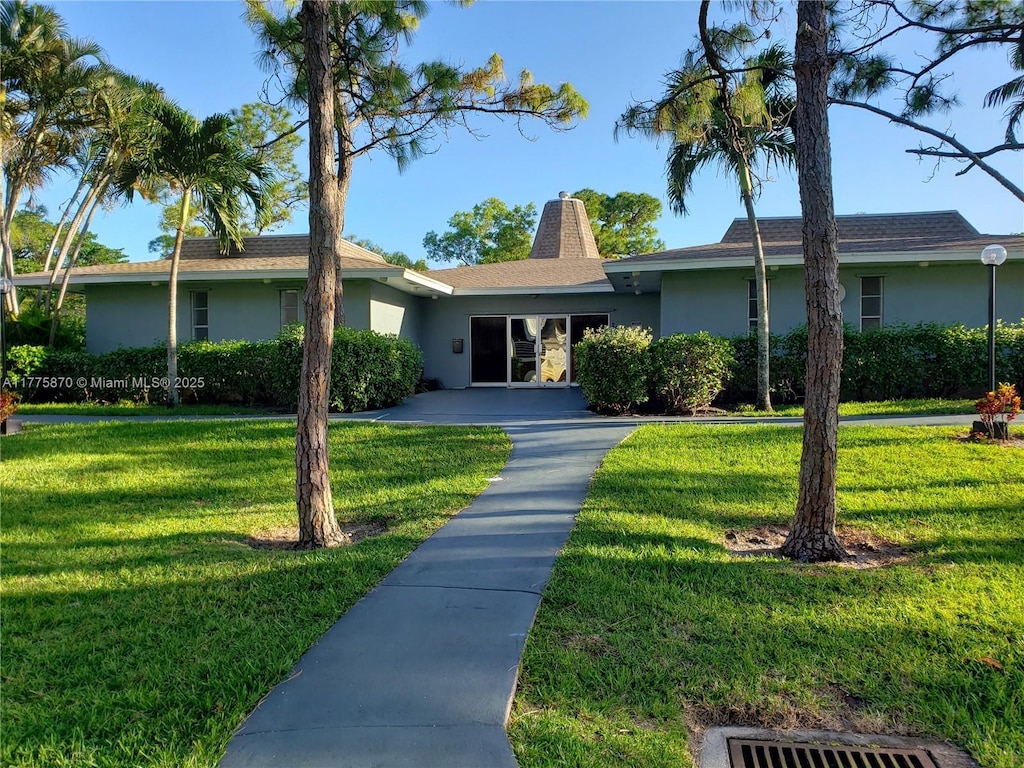 ranch-style house featuring a front lawn and stucco siding