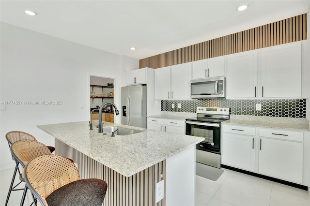 12973SW 266th Ter, Homestead, FL 33032 - kitchen featuring stainless steel appliances, a sink, white cabinets, decorative backsplash, and a breakfast bar