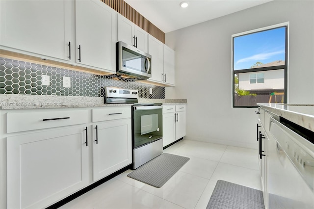12973SW 266th Ter, Homestead, FL 33032 - kitchen with stainless steel appliances, backsplash, white cabinetry, light stone countertops, and light tile patterned floors
