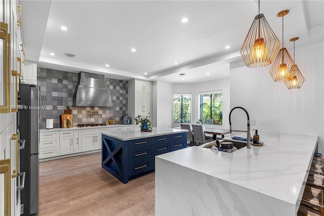 7767 SW 188th St, Cutler Bay, FL 33157 - kitchen with wall chimney range hood, a sink, blue cabinetry, stainless steel appliances, and backsplash
