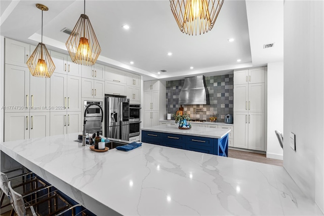 7767 SW 188th St, Cutler Bay, FL 33157 - kitchen with a tray ceiling, wall chimney exhaust hood, appliances with stainless steel finishes, decorative backsplash, and recessed lighting