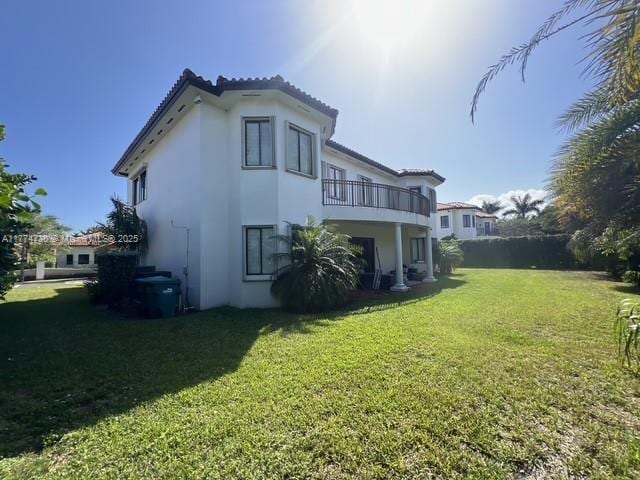 7767 SW 188th St, Cutler Bay, FL 33157 - rear view of house with a balcony, a yard, stucco siding, and a tiled roof