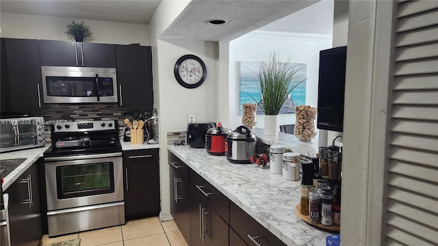 8254 SW 147th Pl, Miami, FL 33193 - kitchen featuring stainless steel appliances, light tile patterned floors, tasteful backsplash, and dark cabinetry
