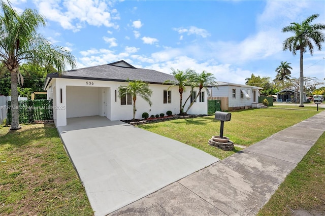 view of front of house featuring fence, a front lawn, stucco siding, driveway, and roof with shingles