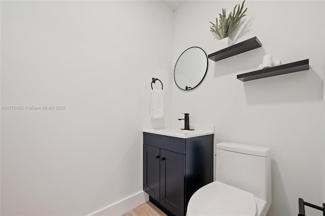 bathroom featuring toilet, vanity, wood finished floors, and baseboards
