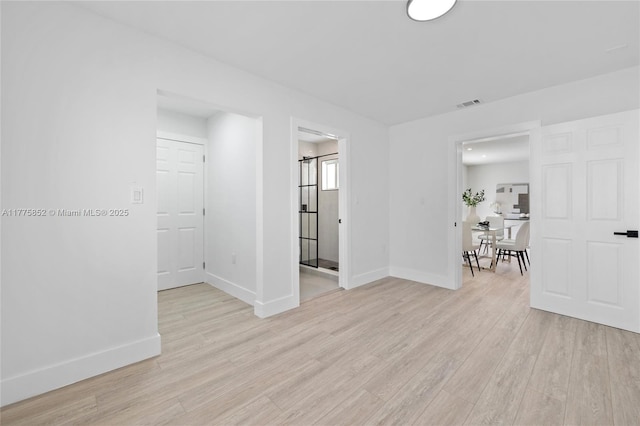 unfurnished room with light wood-type flooring, visible vents, and baseboards