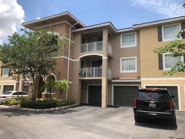 6434 Emerald Dunes Dr Unit 202, West Palm Beach, FL 33411 - view of building exterior featuring an attached garage and driveway