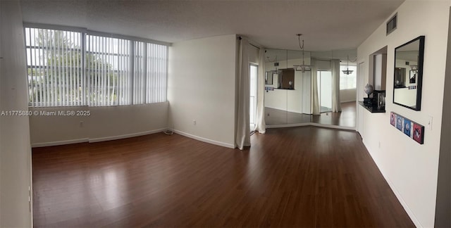 spare room with visible vents, baseboards, wood finished floors, and a wealth of natural light