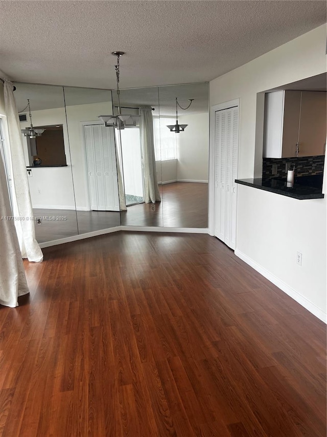 unfurnished dining area with wood finished floors, a textured ceiling, and baseboards
