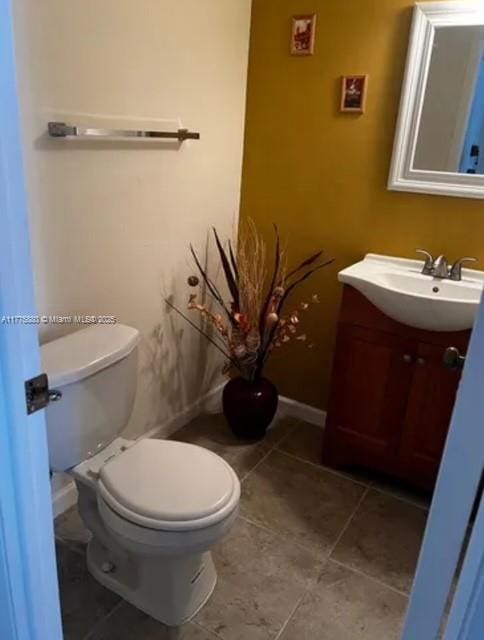 bathroom with baseboards, vanity, tile patterned flooring, and toilet