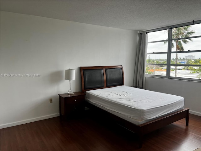 bedroom with baseboards, a textured ceiling, and dark wood-style floors