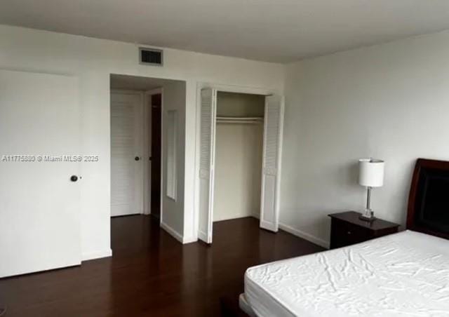 bedroom with wood finished floors, visible vents, and a closet
