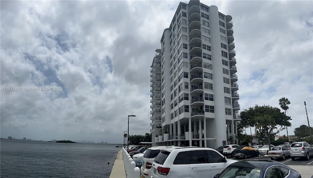 view of building exterior featuring uncovered parking and a water view