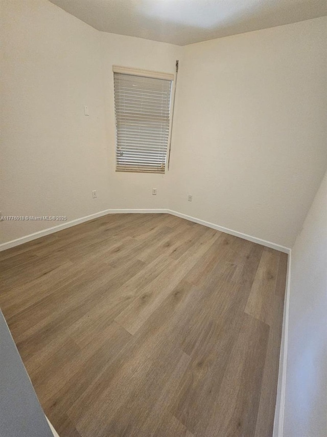 unfurnished room featuring baseboards and wood finished floors