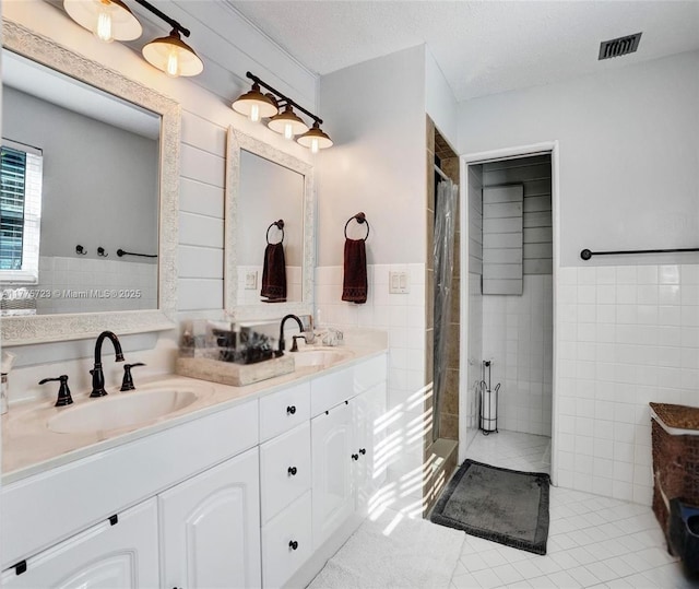 217 SE 5th St, Dania Beach, FL 33004 - full bathroom featuring tile walls, a tile shower, tile patterned flooring, double vanity, and wainscoting