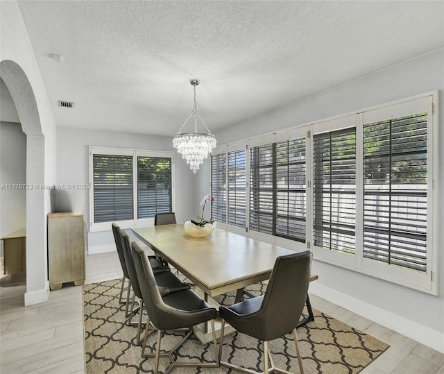 217 SE 5th St, Dania Beach, FL 33004 - dining room featuring arched walkways, a chandelier, a textured ceiling, light wood-type flooring, and baseboards