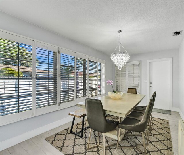 217 SE 5th St, Dania Beach, FL 33004 - dining room featuring healthy amount of natural light, a chandelier, baseboards, a textured ceiling, and light wood-style flooring
