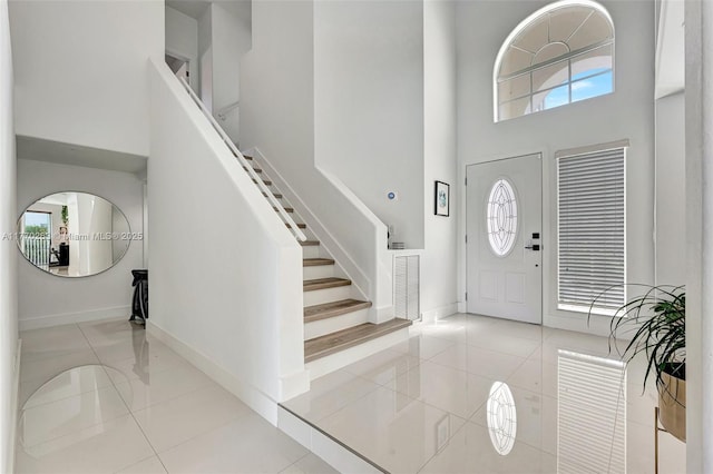 entryway featuring stairway, tile patterned flooring, and a high ceiling
