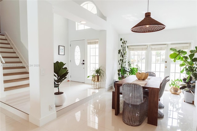 foyer entrance featuring baseboards, stairs, and high vaulted ceiling