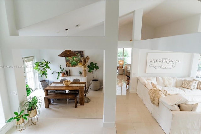 living room with tile patterned flooring, visible vents, and high vaulted ceiling