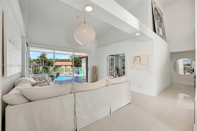 living room with light tile patterned flooring, high vaulted ceiling, and baseboards