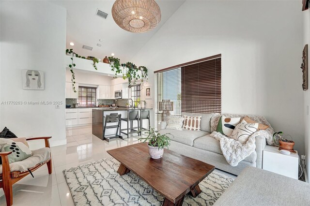 living area featuring visible vents, light tile patterned flooring, and high vaulted ceiling