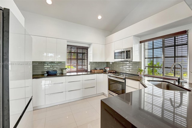 kitchen featuring modern cabinets, white cabinets, tasteful backsplash, a sink, and stainless steel appliances