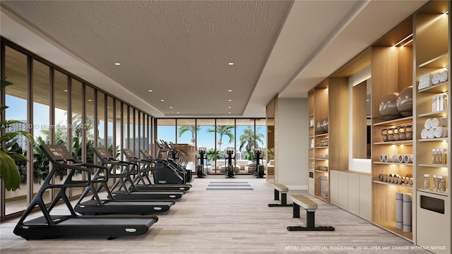 exercise room featuring a wall of windows, wood finished floors, and a textured ceiling
