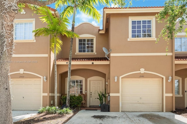 mediterranean / spanish home with stucco siding, a tiled roof, and a garage