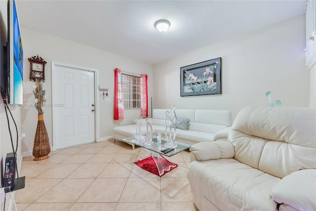 living area featuring a textured ceiling, baseboards, and light tile patterned floors