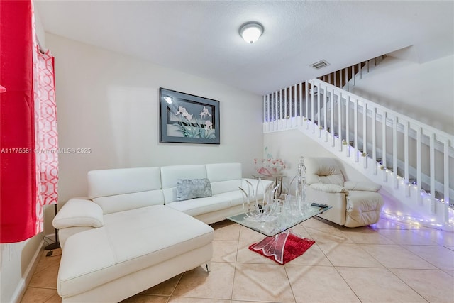 living area featuring visible vents, tile patterned flooring, and stairs