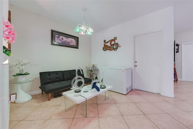living area featuring an inviting chandelier, light tile patterned flooring, and baseboards