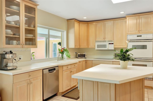 kitchen with light brown cabinets, white appliances, a sink, and light tile patterned floors