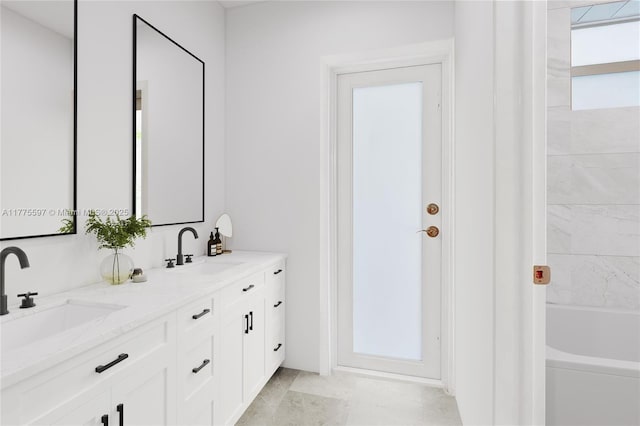 bathroom featuring a tub to relax in, double vanity, and a sink