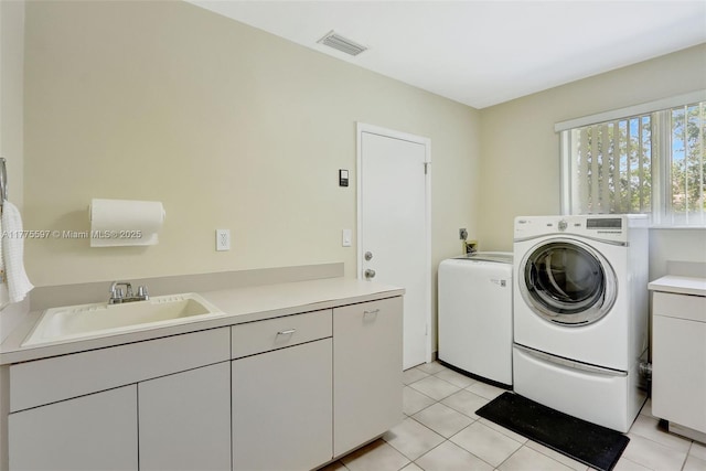 washroom featuring washer and clothes dryer, cabinet space, a sink, and visible vents