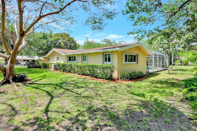 view of side of home featuring a lawn, a lanai, and stucco siding