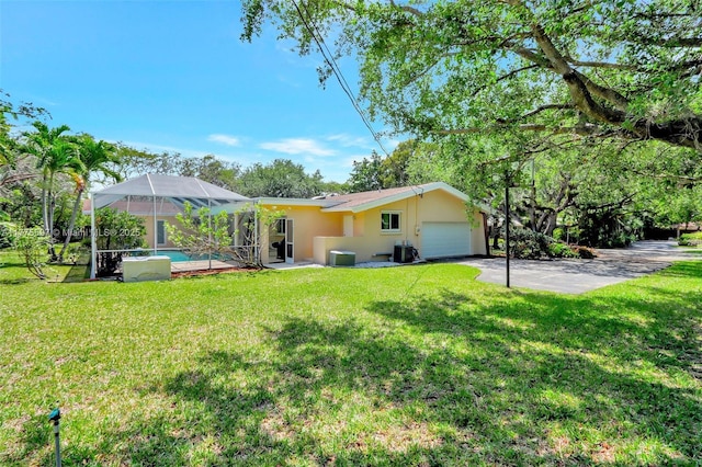 rear view of house with a lanai, central AC, an attached garage, a yard, and stucco siding