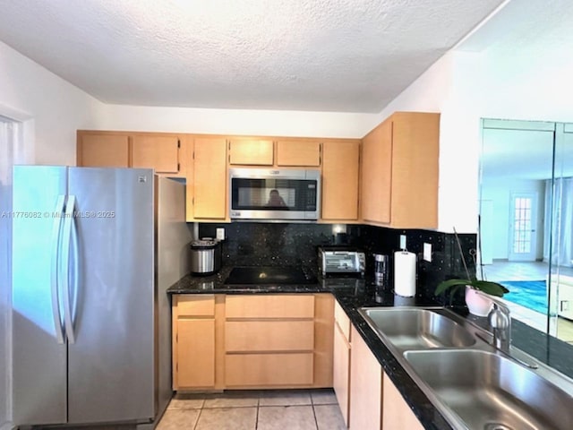 kitchen with decorative backsplash, a sink, dark countertops, light brown cabinets, and appliances with stainless steel finishes