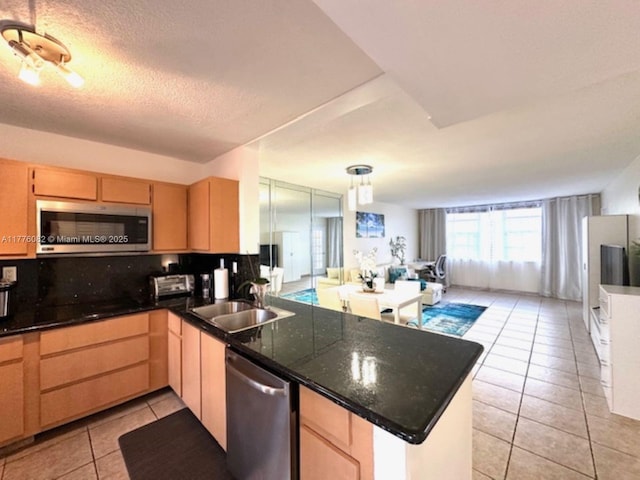 kitchen with light brown cabinets, a sink, appliances with stainless steel finishes, a peninsula, and light tile patterned floors