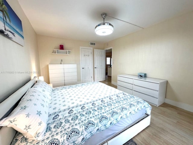 bedroom with baseboards, visible vents, and wood finished floors