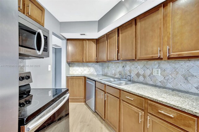 6911 Environ Blvd Unit 3L, Lauderhill, FL 33319 - kitchen with appliances with stainless steel finishes, a sink, backsplash, light stone counters, and brown cabinets