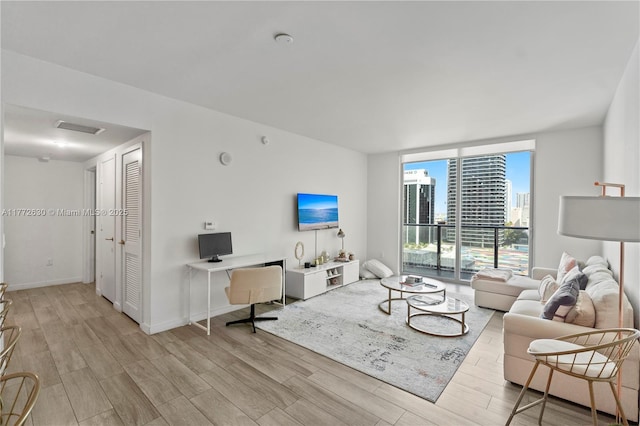 living area with baseboards, floor to ceiling windows, wood finished floors, and visible vents