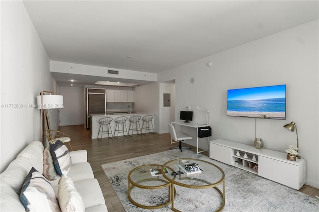 living room with visible vents, electric panel, and light wood-type flooring