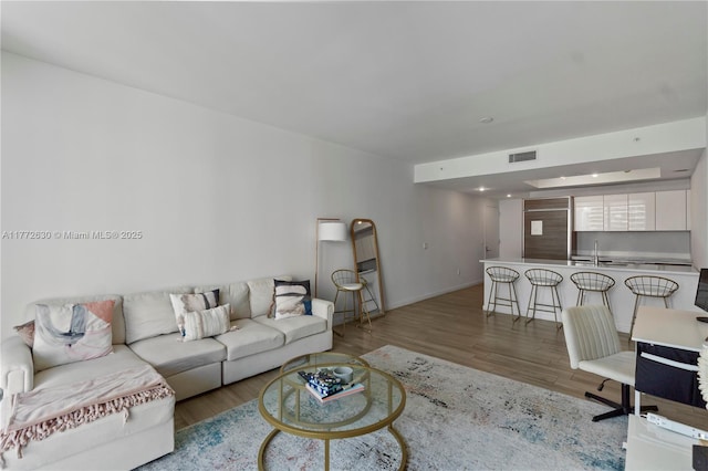 living area with visible vents, baseboards, and wood finished floors