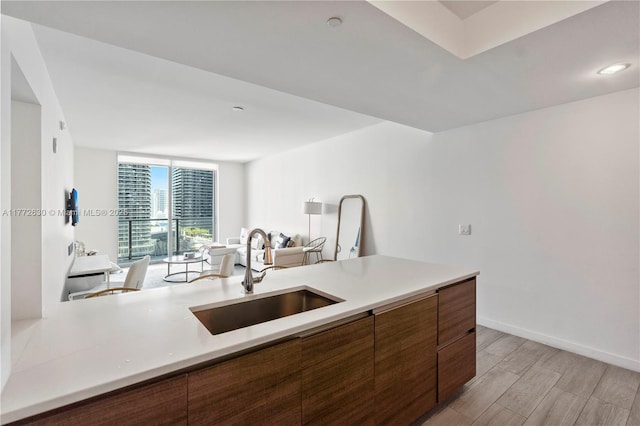 kitchen featuring a sink, light countertops, brown cabinetry, and light wood-style flooring