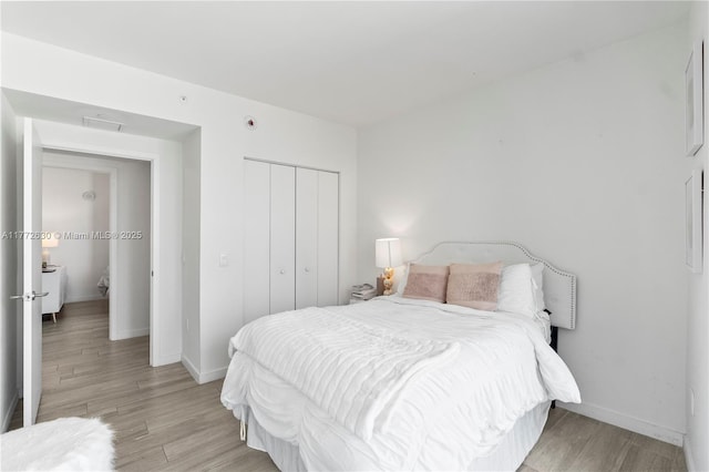 bedroom featuring baseboards, visible vents, light wood finished floors, and a closet