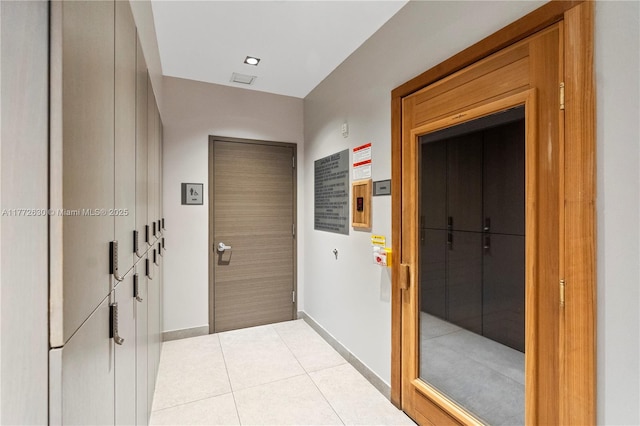 interior space with baseboards, tile patterned floors, and elevator