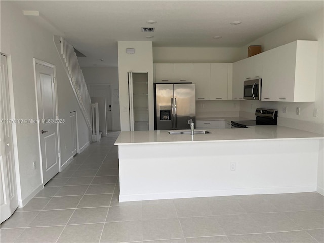 12179 NW 23rd Ct, Miami, FL 33167 - kitchen featuring appliances with stainless steel finishes, light countertops, a peninsula, and light tile patterned flooring