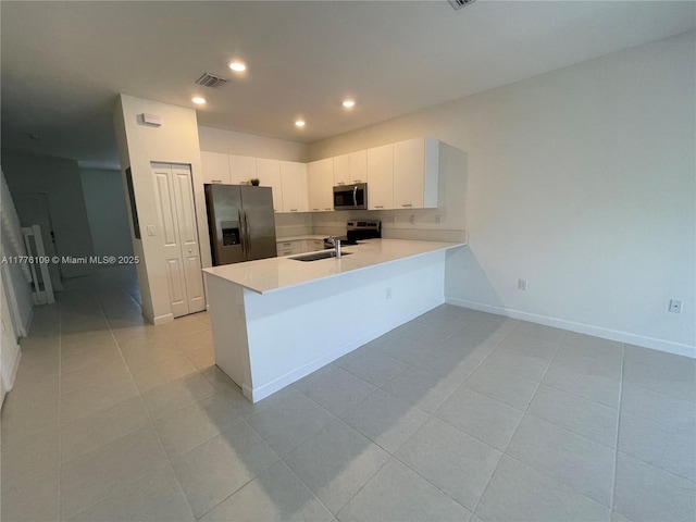 12179 NW 23rd Ct, Miami, FL 33167 - kitchen featuring appliances with stainless steel finishes, a peninsula, light tile patterned floors, light countertops, and recessed lighting