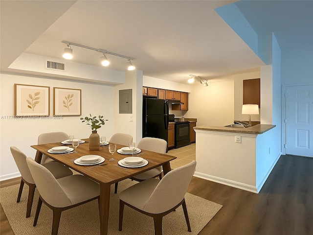 dining area with electric panel, baseboards, visible vents, and light wood finished floors
